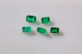 Five small rectangular green emerald gemstones arranged