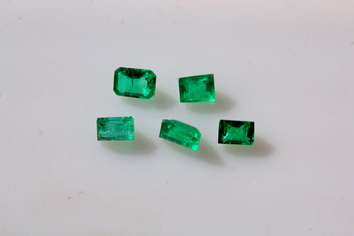 Five small rectangular green emerald gemstones arranged